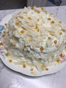White cake with coconut flakes and some kind of candied citrus bits